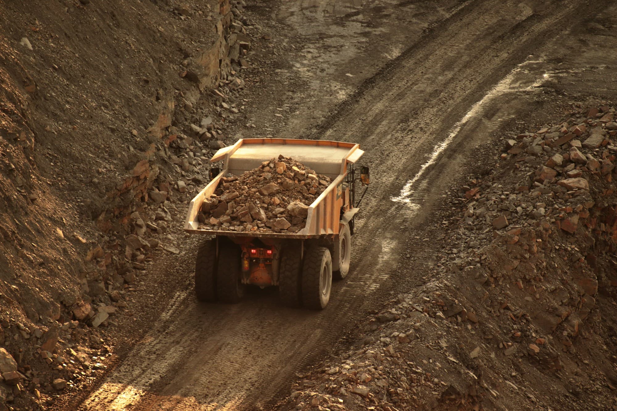 Ore trucks on a rough mountain haul route toward the border crossing