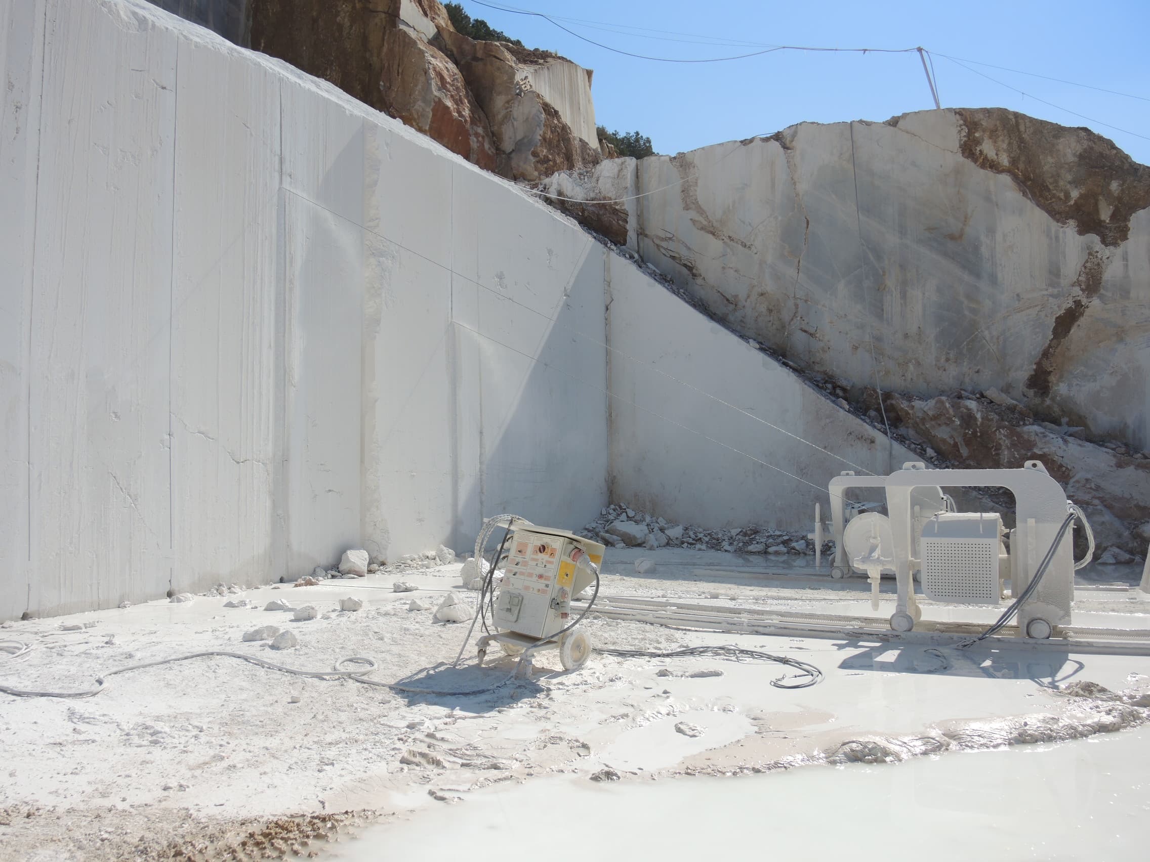 Chain saw quarrying machine cutting dry into a white marble bench